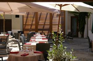 ein Restaurant mit weißen Tischen und weißen Sonnenschirmen in der Unterkunft Logis Hôtel Le Cheval Noir in Argenton-sur-Creuse
