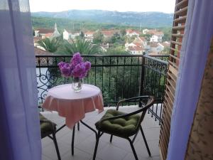 a table with a vase of purple flowers on a balcony at Villa Agava in Vrboska