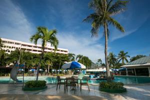 un complejo de piscina con mesas, sillas y palmeras en Asia Pattaya Hotel, en Pattaya South