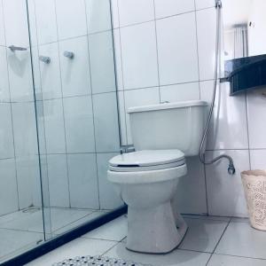 a white bathroom with a toilet and a shower at Pousada Amazonas in Itabuna