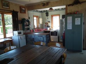 een keuken met een houten tafel en een koelkast bij Mountains Edge Cabins in Monowai