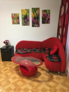 a living room with a red couch and a glass table at Apartment Bombonyerka in Drogobych