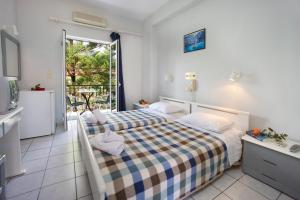 a bedroom with two beds and a balcony at Hotel Athina in Karavomylos