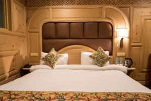 a bedroom with a large bed with a large headboard at Hotel Imperial Resorts in Sonāmarg