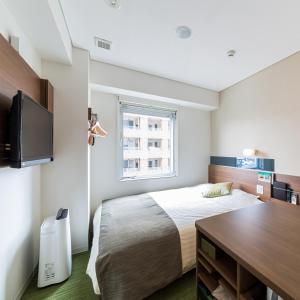 a bedroom with a bed and a desk and a tv at Super Hotel Premier Hakataeki in Fukuoka