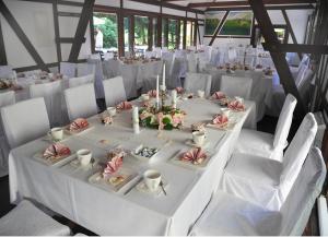 a long white table with white chairs in a room at Hotelanlage Starick in Lübbenau