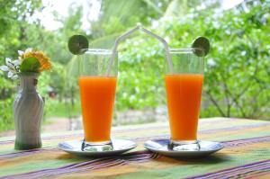 due bicchieri di succo d'arancia seduti su un tavolo di Rock Lake Home Stay a Sigiriya