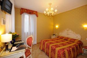 a hotel room with a bed, chair, lamp and window at Hotel Il Mercante di Venezia in Venice
