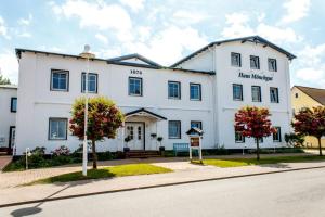 un gran edificio blanco con árboles delante de él en Hotel Haus Mönchgut, en Thiessow