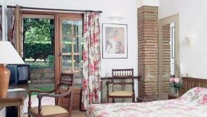 a bedroom with a bed and chairs and a window at Le Ratelier in Montaigut-sur-Save