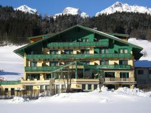 a large building in the snow with snow capped mountains at Hotel Druschhof in Schladming