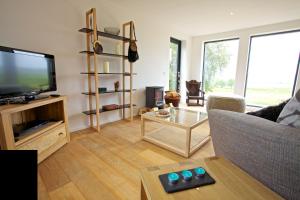 ein Wohnzimmer mit einem Sofa und einem TV in der Unterkunft Skeabost Wood Cottage in Skeabost