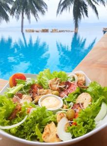 un plato de ensalada en una mesa junto a una piscina en Sun Beach Bungalows, en Haad Rin