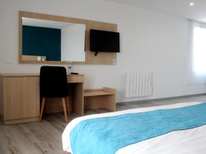 a bedroom with a bed and a desk and a television at Saglam Hôtel in Goussainville