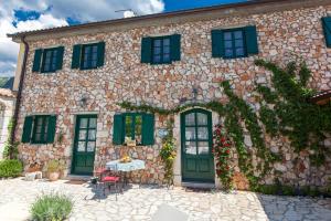 a large stone building with green doors and windows at Villa Oliva Bribir in Bribir