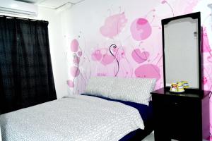 マラッカにあるbranded hotelのピンクの壁、ベッド1台付きのベッドルーム1室