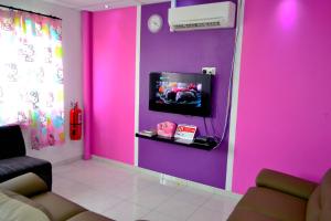 a living room with a pink wall with a tv at branded hotel in Malacca