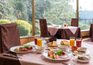 Hachinohe Park Hotel في هاتشينوه: طاولة مع أطباق من الطعام وكؤوس من عصير البرتقال