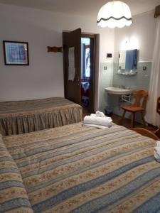 コルティーナ・ダンペッツォにあるHotel Fiamesのベッド2台とシンク付きのホテルルームです。
