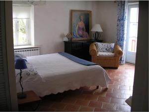 een slaapkamer met een bed en een stoel en een schilderij bij Chambres d'Hôtes Oyhanartia in Larceveau-Arros-Cibits