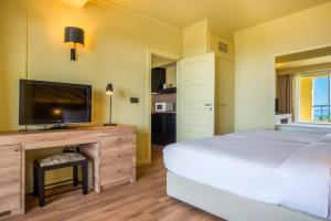 a bedroom with a bed and a desk with a television at Calheta Beach - All-inclusive - Savoy Signature in Calheta