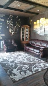 a living room with leather couches and a carpet at Dom v Belovezhskoi Pushcie in Kamenyuky