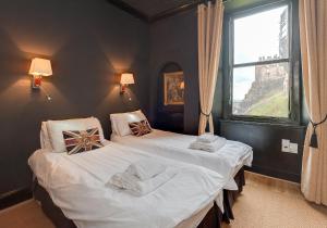 two twin beds in a room with a window at The Castle Esplanade Residence in Edinburgh