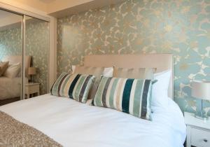 エディンバラにあるThe Drummond Street Residenceの花柄の壁の白いベッドが備わるベッドルーム1室が備わります。