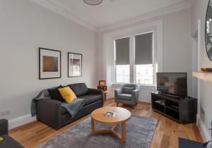 een woonkamer met een bank en een tv bij The Brunswick Street Residence in Edinburgh