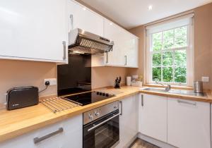 La cuisine est équipée de placards blancs et d'un four avec plaques de cuisson. dans l'établissement Castle Suite 1 Old Town, à Édimbourg