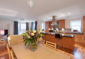 een keuken en een woonkamer met een vaas met bloemen op een tafel bij The Holyrood Park Residence in Edinburgh