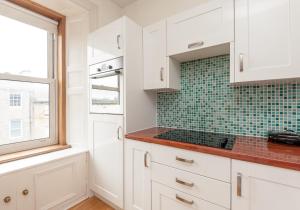 エディンバラにあるThe Lothian Road Residenceの白いキャビネットと窓付きのキッチン