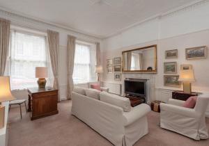 uma sala de estar com mobiliário branco e uma lareira em The Hart Residence em Edimburgo