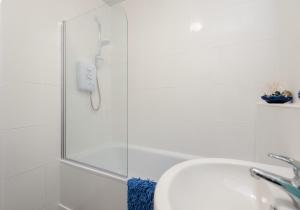 a shower with a glass door next to a sink at The Portsburgh Square Residence in Edinburgh