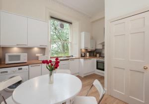 uma cozinha branca com uma mesa branca com flores em The Hart Residence em Edimburgo