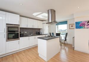 une cuisine avec des armoires blanches et un comptoir dans l'établissement The Metropole Residence, à Glasgow