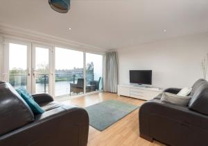 a living room with two leather couches and a television at The Metropole Residence in Glasgow