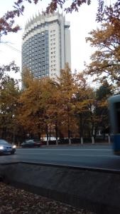 a large building in front of a road with trees at Hostel Viator in Almaty