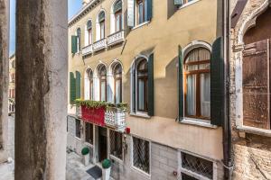 un edificio con ventanas de contraventanas verdes en una calle en Ca' del Monastero 6 Collection Chic Apartment for 4 Guests with Lift, en Venecia