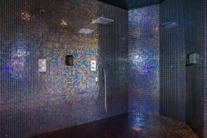 a blue tiled bathroom with a shower with blue lights at Calheta Beach - All-inclusive - Savoy Signature in Calheta