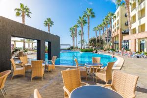 un patio extérieur avec des tables et des chaises à côté d'une piscine dans l'établissement Calheta Beach - All-inclusive - Savoy Signature, à Calheta