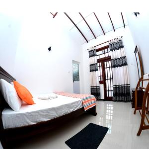 a bedroom with a bed with orange pillows and a window at Reshani Guest House in Negombo