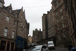 two cars are parked on a city street with buildings at 27/3a Cockburn Street Apartments in Edinburgh