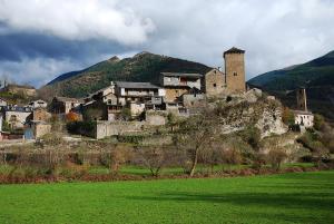 a group of buildings on a hill with a green field at Casa Alba Ara in Oto
