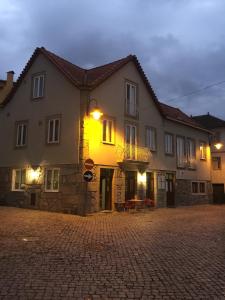 a large building on a cobblestone street at night at Casas do Terreiro in Seia