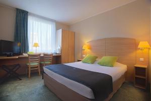 a hotel room with a bed and a desk and a television at Campanile Lublin in Lublin