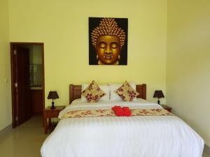 een slaapkamer met een groot bed met een gouden masker erop bij Amed Kunara Guest House in Amed