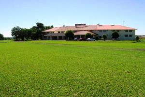 un gran campo verde con un edificio en el fondo en Executivo Park Hotel, en São Borja