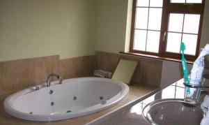 a bathroom with a bath tub and a sink at Beautiful Home on Lake Carrowmore in Belmullet