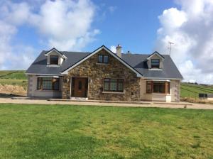 a stone house with a green lawn in front of it at Beautiful Home on Lake Carrowmore in Belmullet